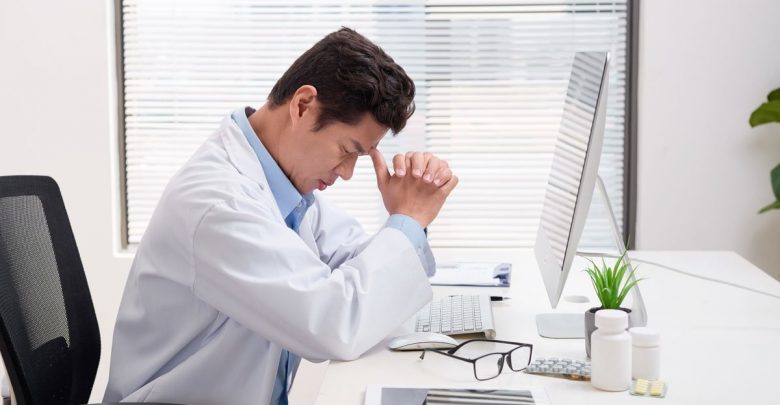 stressed doctor with head in hands