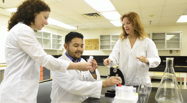 Graduate student Jonas Gomez works with professors in the lab.