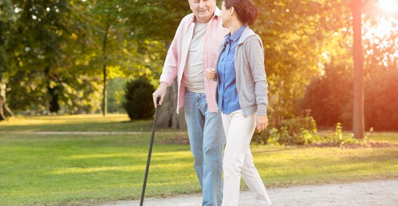Older man and caregiver going on a walk outside